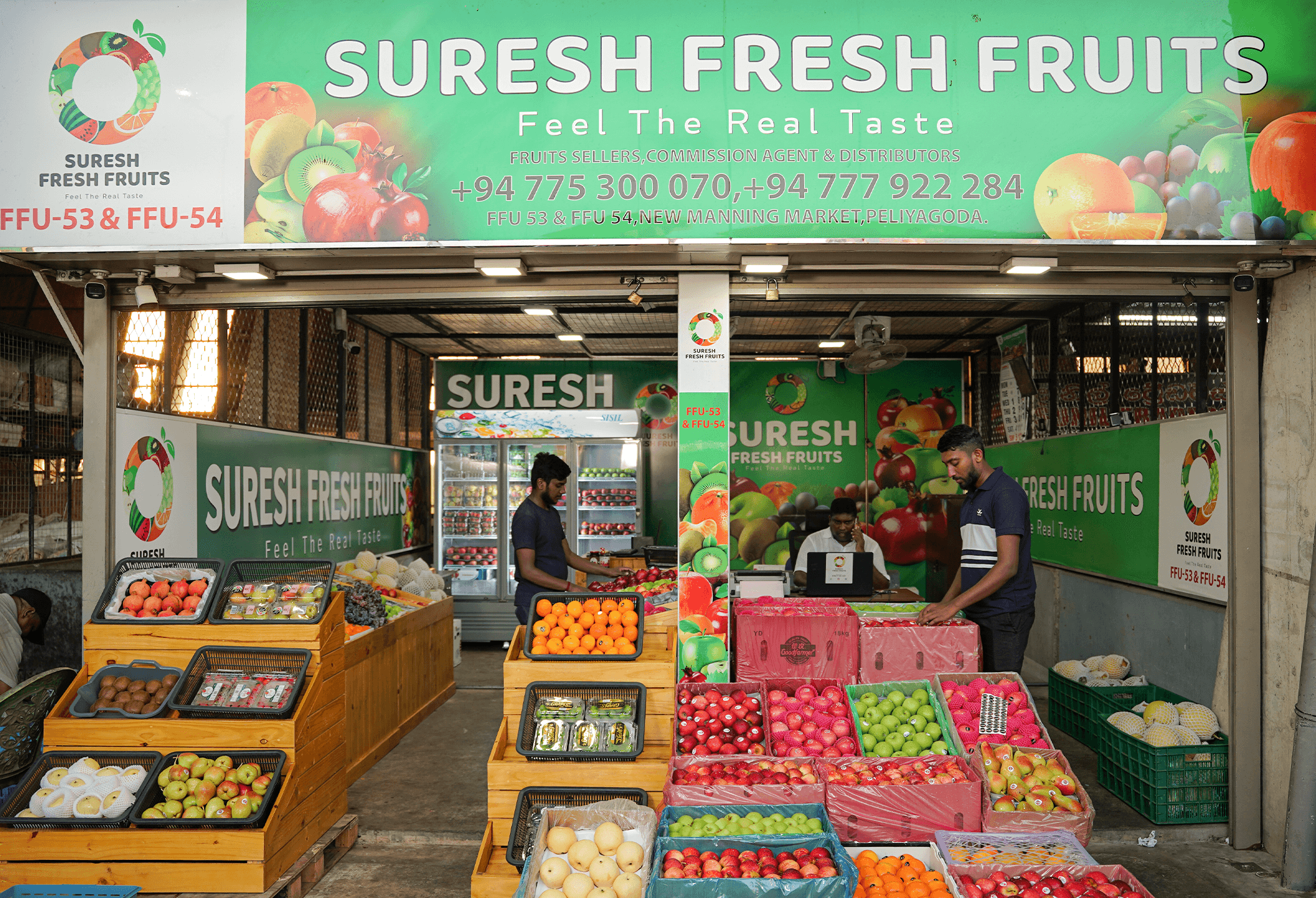 Suresh Fresh Fruits market stall with green banner, staff and fresh fruit crates