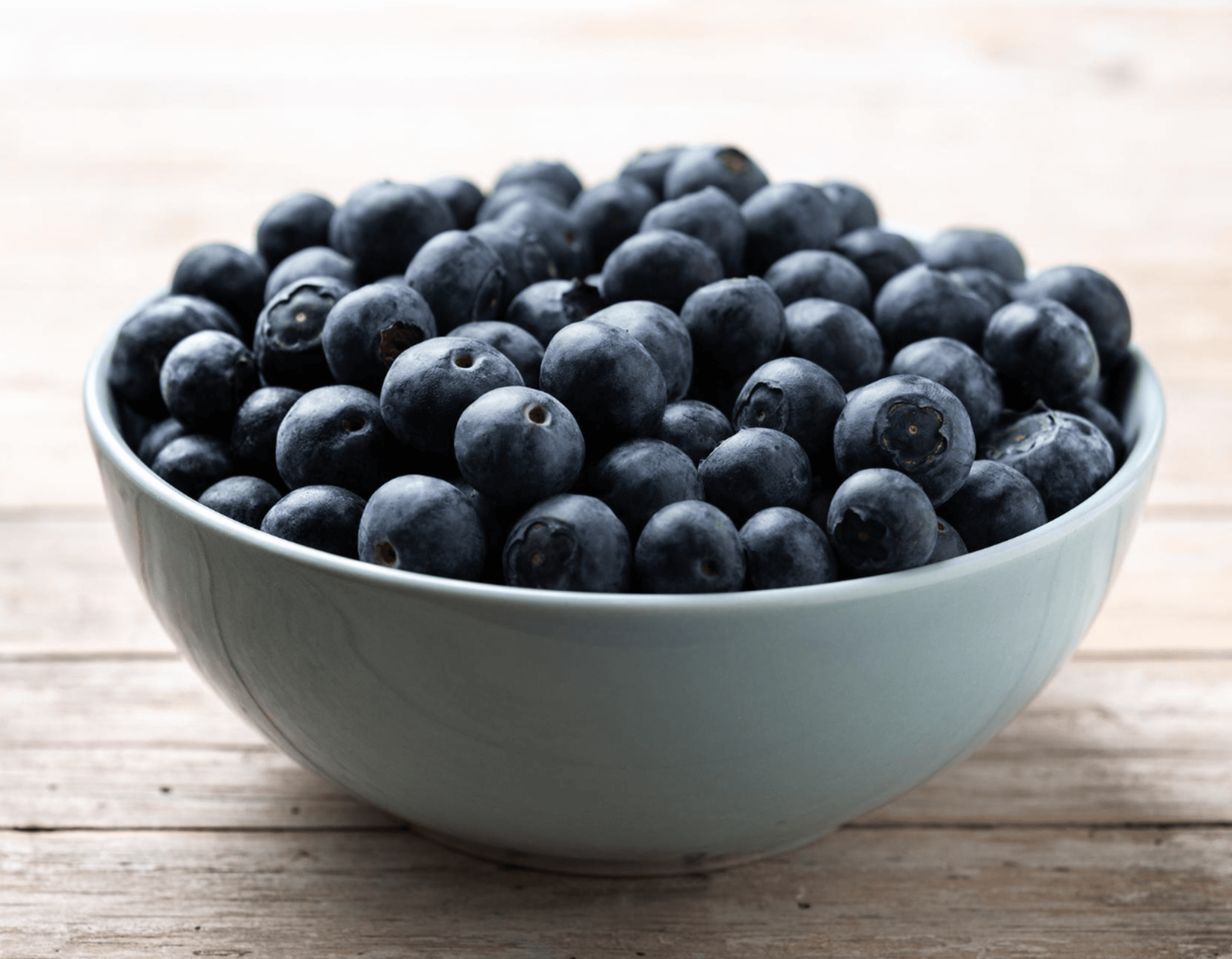 A ceramic bowl filled with fresh ripe blueberries