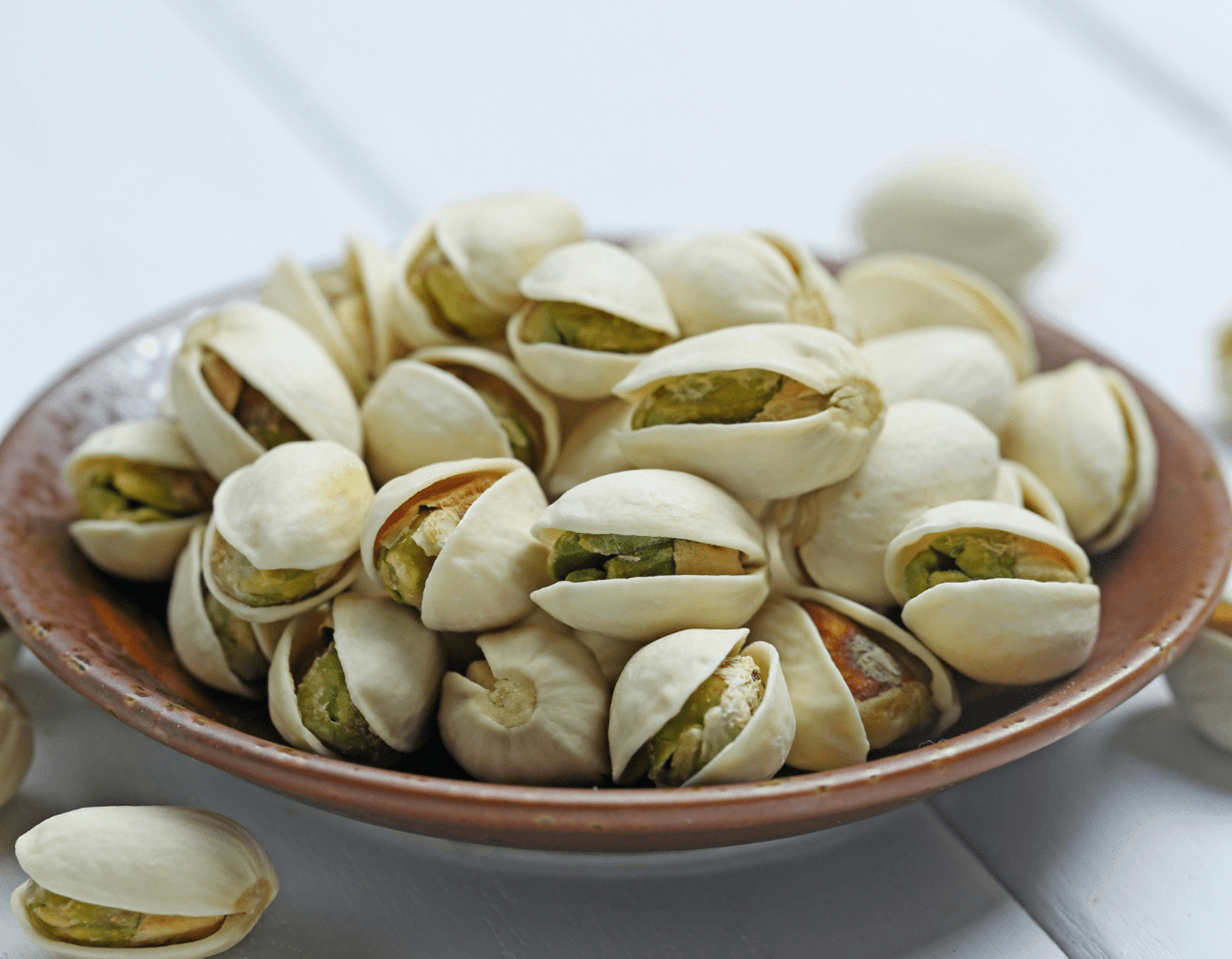 Roasted pistachios in shell served in a ceramic bowl