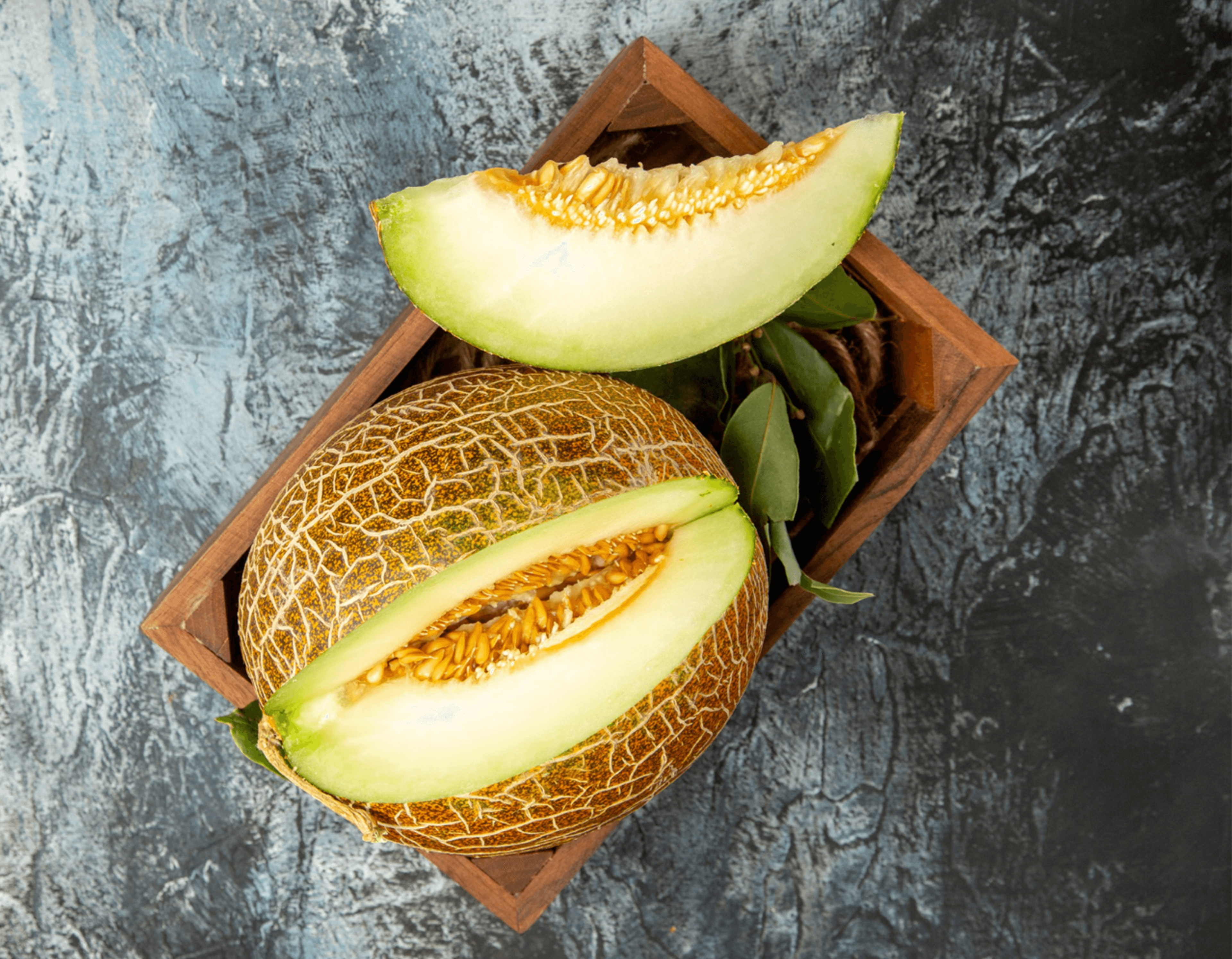Fresh honeymelon with pale green flesh displayed in a wooden crate
