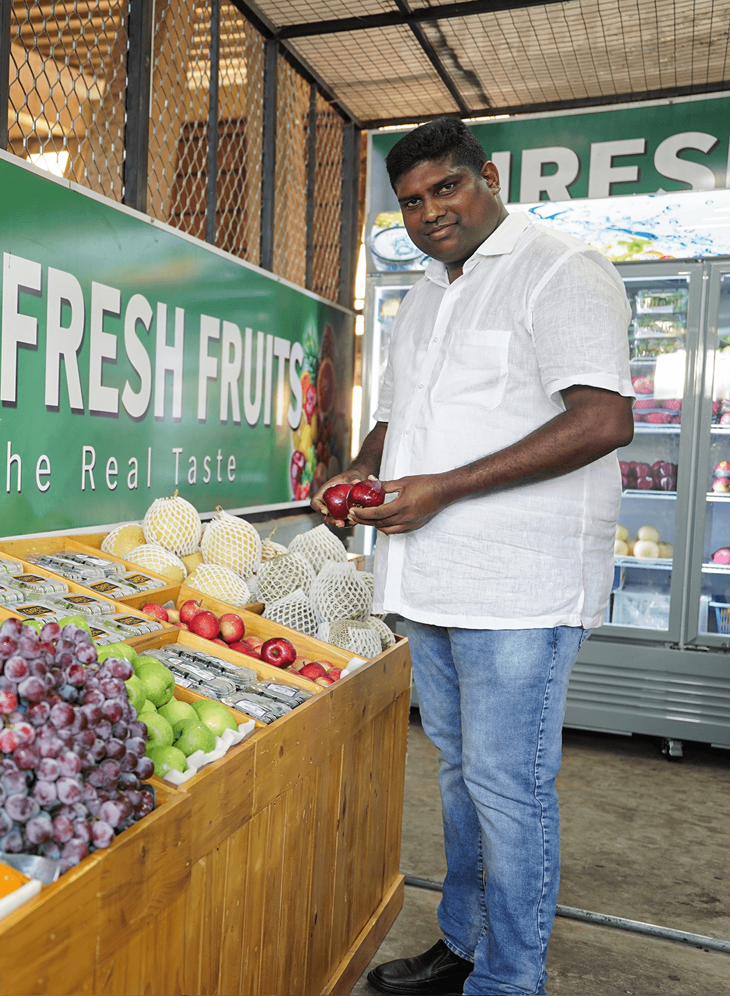Suresh Fresh Fruit founder holding red apples at the market stall