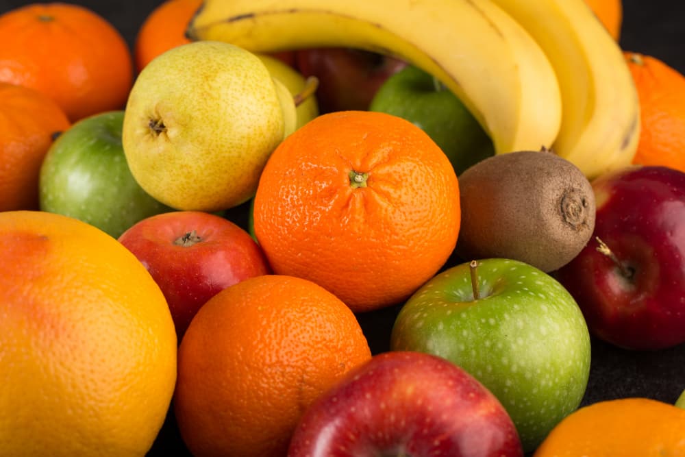 Fresh oranges, red and green apples, bananas, pear and kiwi arranged together
