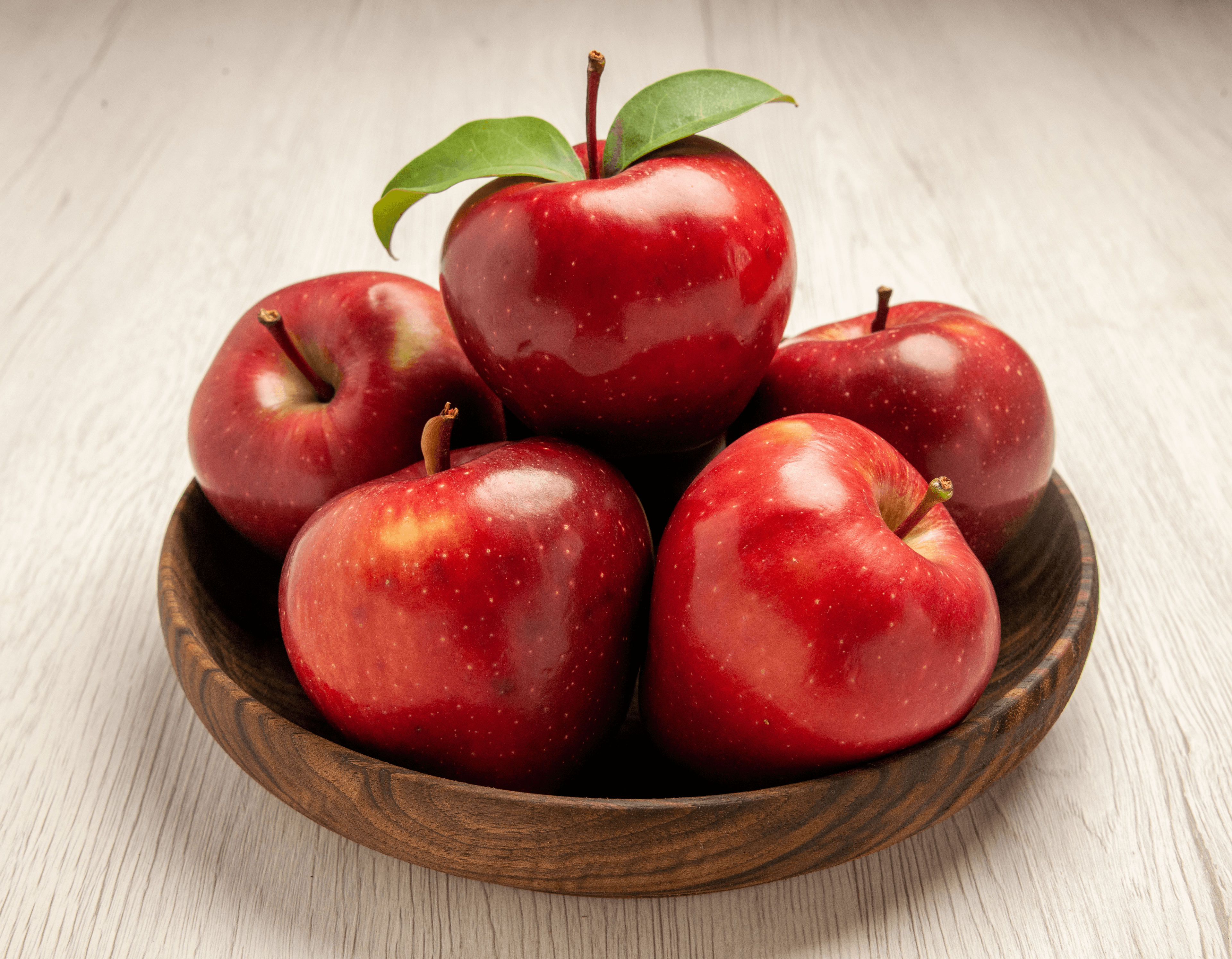 Fresh red apples in a wooden bowl for commercial produce display
